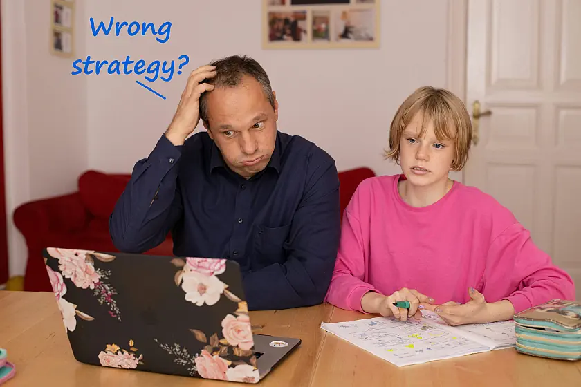 father and daughter doing maths homework looking confused at computer screen
